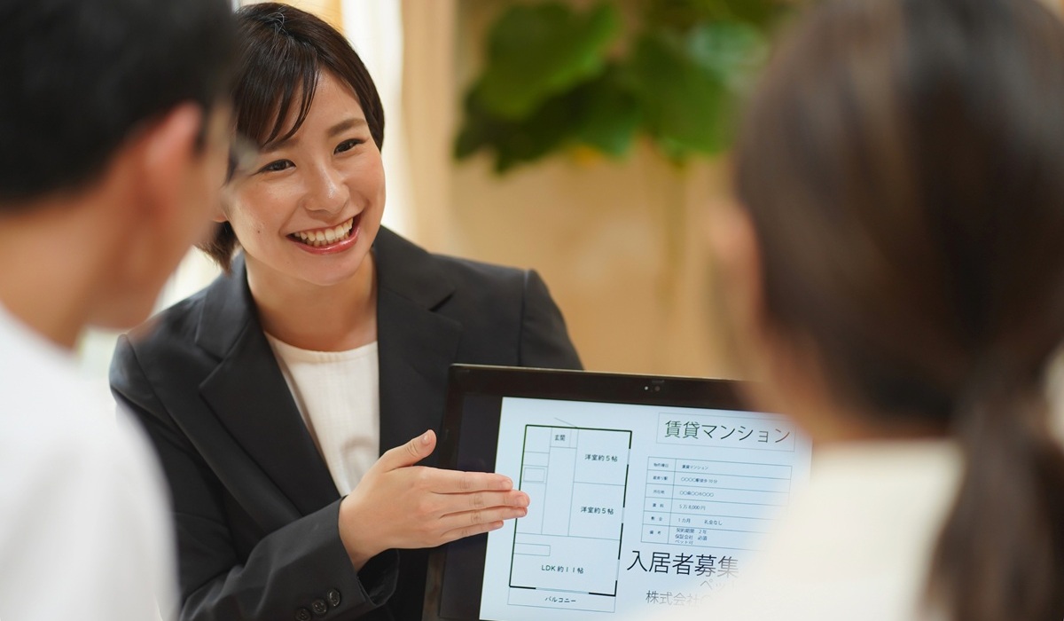 不動産会社の担当者がタブレットの賃貸情報を笑顔で顧客に説明している様子