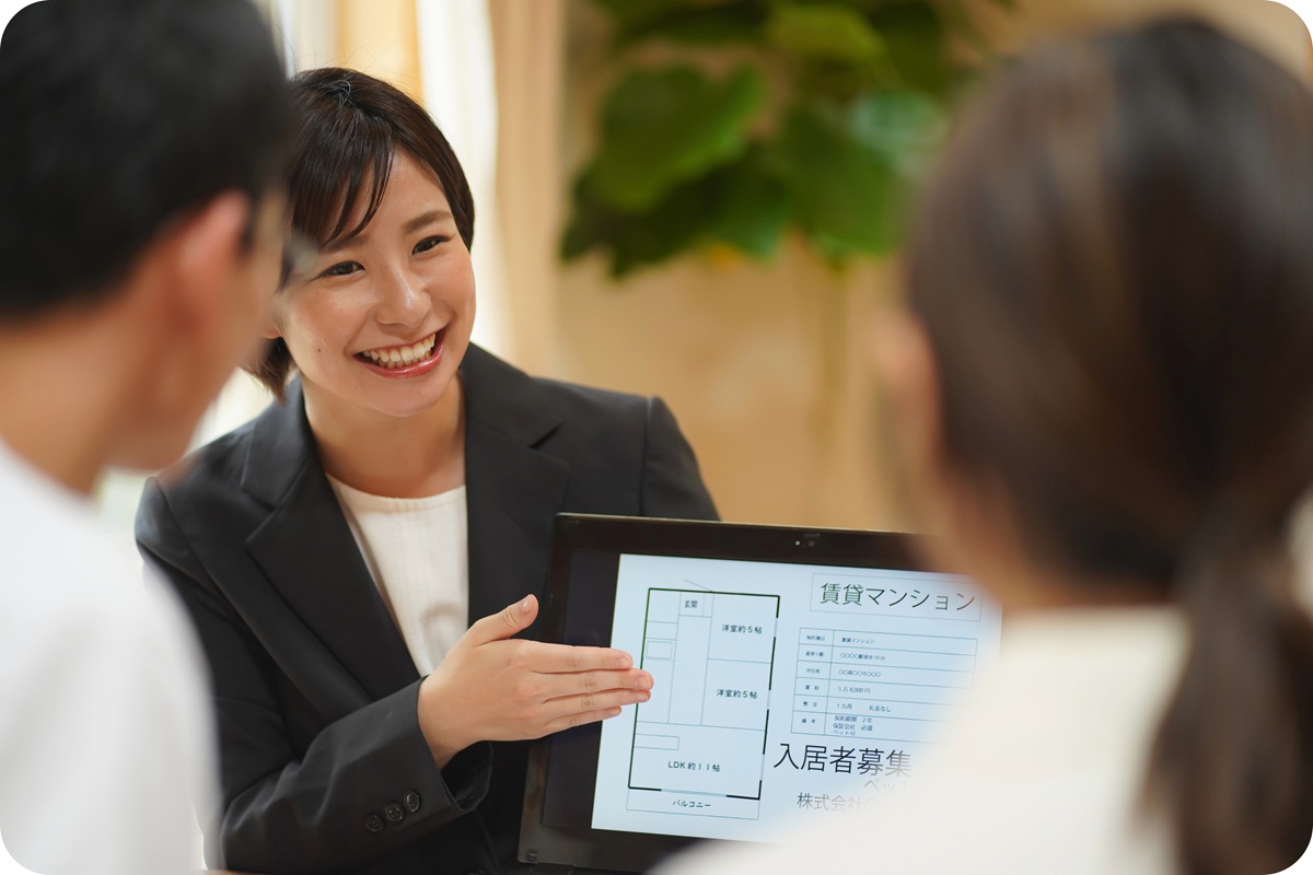 不動産会社の担当者がタブレットの賃貸情報を笑顔で顧客に説明している様子